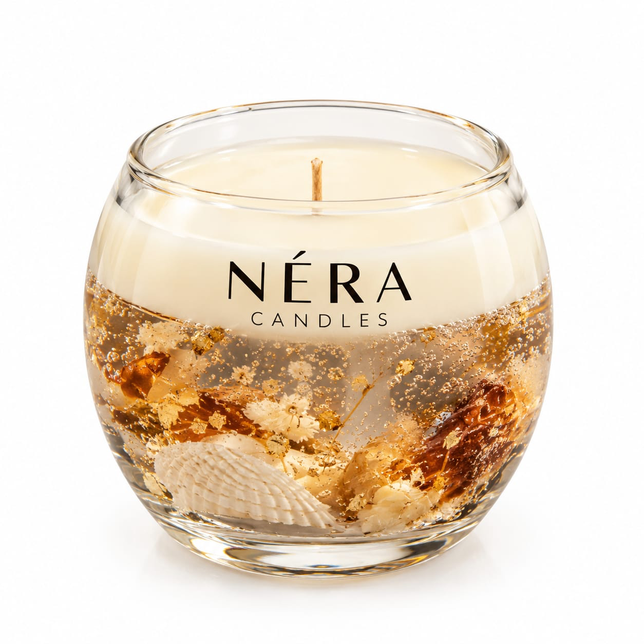 NÉRA nature candle in a round glass with seashells, dried flowers and golden details beneath creamy wax
